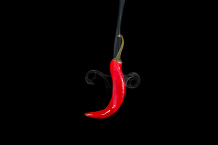 Smoking red hot chili pepper. Close up studio shot of spice floating in air on black background with smoke.の写真素材