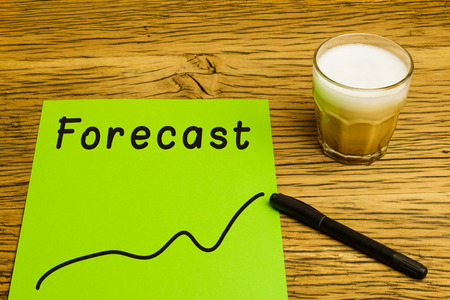 Forecast written on green paper with graph. Marker and coffee on desk.の写真素材