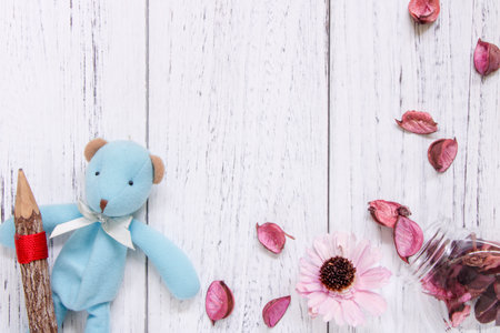 Flat lay stock photography vintage white painted wood floor purple flower petals glass bottle blue bear doll holding pencilの写真素材