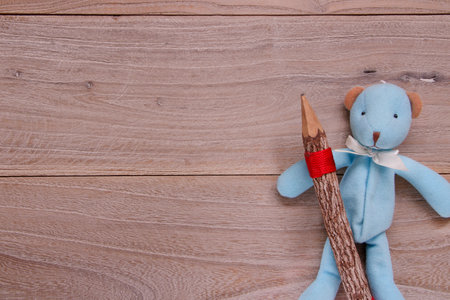 Stock photography flat lay template blue bear doll holding wooden pencil on plank table