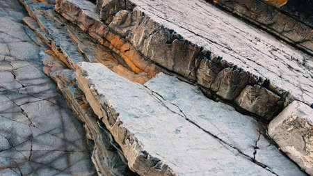 Cracked and eroded cliff wall revealing sedimentary rock layers along the Cornish coastline.