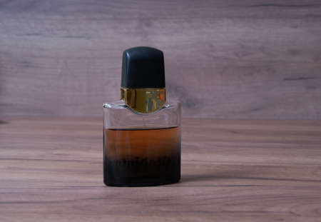 a bottle of dark cologne standing on a wooden tableの写真素材