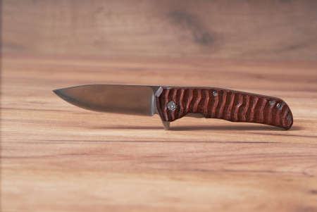 Hunting knife on a wooden background made of high quality stainless steel.