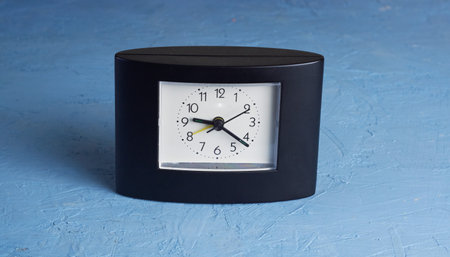 black square clock on light blue backgroundの写真素材