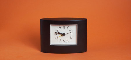 black square clock on light brown backgroundの写真素材