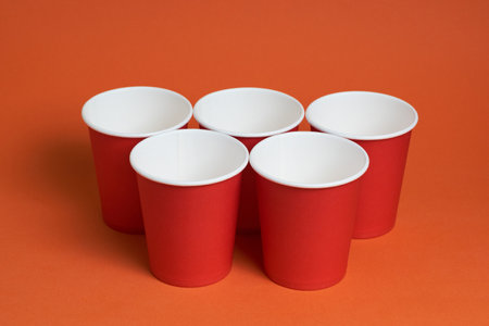 Five red disposable cups on a brown background. Place for textの写真素材