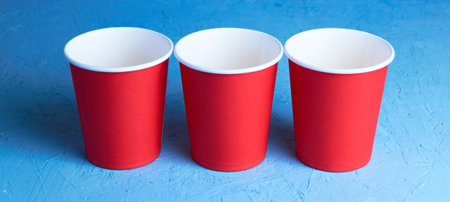 Three red disposable cups on a blue background. Place for textの写真素材