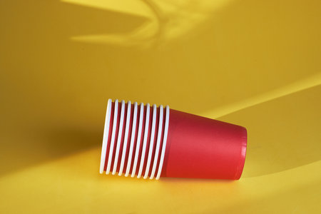 bright red disposable cups on a yellow background disposable tablewareの写真素材