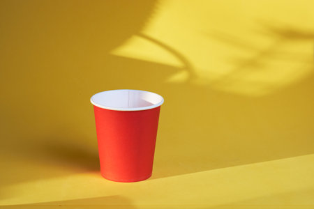 Red disposable coffee cup to take away on a yellow backgroundの写真素材