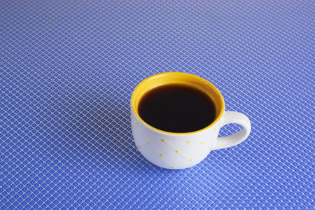 yellow cup of coffee on a blue backgroundの写真素材
