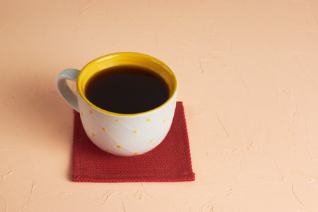 White and yellow cup with black coffee on pink backgroundの写真素材