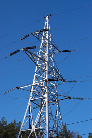 the pylons of a power line with sun and blue skyの写真素材
