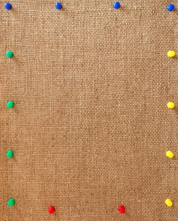 Burlap background with the varicolored pins made a frameの写真素材