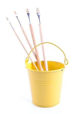 Childish pail with the paintbrushes isolated on whiteの写真素材