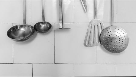 Background Made with Kitchen Utensils Hanging on the White Tileの写真素材
