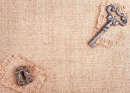 Burlap Background with Keyhole and Key in the Cornersの写真素材