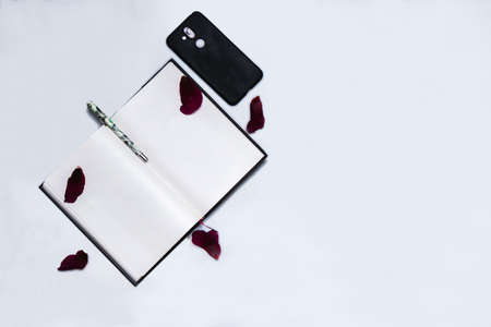Flat-lay open note book on a white background with a mobile and pen.の写真素材