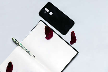 Flat-lay open note book on a white background with a mobile and pen.の写真素材