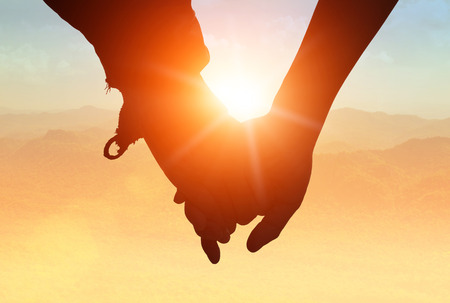 silhouettes on sunset of loving couple holding hands while walking at on Mount stacked.の写真素材