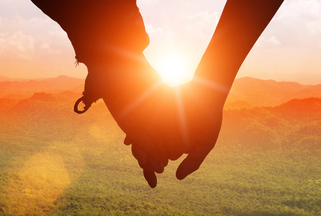 silhouettes on sunset of loving couple holding hands while walking at on Mount stacked.の写真素材
