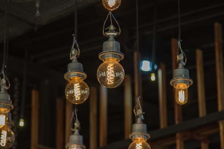 Lighting on the chandelier in the lamplight, light bulbs hanging from the ceiling, lamps on the dark background .Coffee Shop Decoration .の写真素材