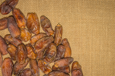 Dried date fruits on sackcloth brown background.の写真素材