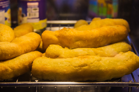 Big deep fried dough sticks in put on a stainless steel sieve of hot cooking colorful in the early morning.の写真素材