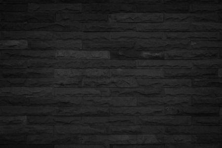 Wall dark black brick texture background. Brickwork or stonework flooring interior backdrop grunge grey wallpaper rock old at pattern concrete grid surface uneven sandstone design for copy space.の写真素材
