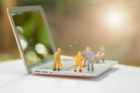 Miniature worker people or small figure cleaning computer maintenance model as electronic repair and technology development concept. Cleaning team work on engineer fixing broken computer motherboard.の写真素材