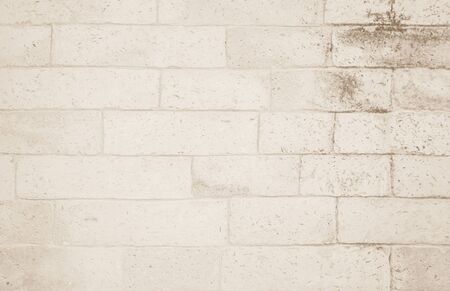 Background of wide cream brick wall texture. Old brown brick wall concrete or stone wall textured, wallpaper limestone abstract flooring/Grid uneven interior rock. Home or office design backdrop.の写真素材