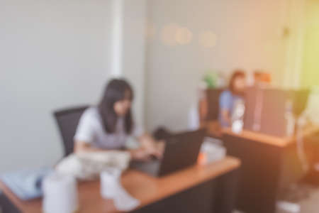 Business women blur in the workplace at sitting on a computer screen work space on table desk work in office blurry, document division and people shallow depth of focus horizontalの写真素材