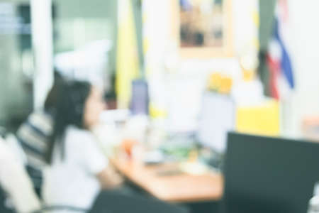 Business woman blur in the workplace at sitting with desk computer screen work space of table in office workers, interior modern design, people with document and laptop.の写真素材