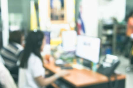 Business woman blur in the workplace at sitting with desk computer screen work space of table in office workers, interior modern design, people with document and laptop or depth.の写真素材