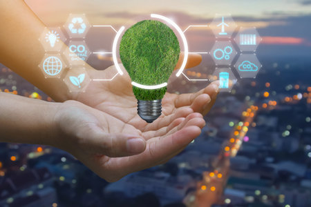 Hand holding green world map on light bulb. Renewable energy and sustainable development - Ecology global sustainability concept. Saving environment on with renewable energy sourceの写真素材