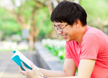 Young Asian man reading book in the parkの写真素材