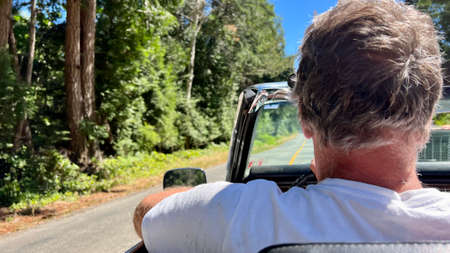 a man driving a convertible rides in the forest on the road he has gray hair he is 60 years old travel travel by carの写真素材