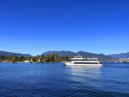 The white yacht sails slowly from right to left calm no wind Clear blue sky and smooth ocean water in the background mountains are visible Canada Vancouver 09.2022のeditorial素材