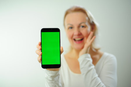 Chroma Key Phone green screen space for advertising Hurray Victory has found Fabulous Photo of a woman in a white T-shirt on a white background Beautiful adult happy woman different emotionsの写真素材