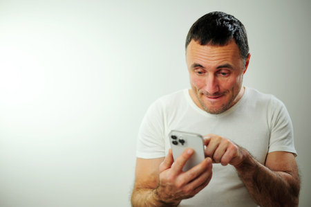 Positive millennial man showing huge brand new smartphone with empty screen and thumb up over white studio background, mockup, panorama with copy space, newest mobile app conceptの写真素材