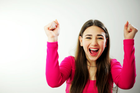 Place for text advertising sales Insanely beautiful young woman girl with long brown hair in a pink sweater on a white background different emotions Many positive emotions joy happiness fun successの写真素材