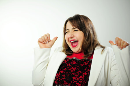 Life is wonderful Joyful lady keeps fists clenched, tilts head and exclaims in triumph, celebrates success, with blank space for your advertisement happy and cheerful smiling moving casual confidentの写真素材