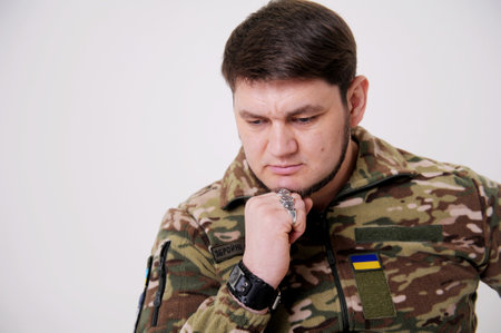 Ukrainian soldier leaned his head on hand and thought he looks down he has beautiful blue eyes beard and uniform. a lot of pain and sadness in his eyes. the war changed life. Russia attacked Ukraineの写真素材