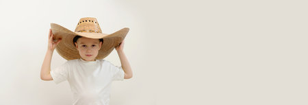 banner for billbard space for headwear advertising for kids leisure travel boy in cowboy hat in white t-shirt in studio hands near hat handsome face smile kindergarten family happy childhood good luckの写真素材