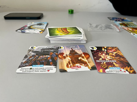 Young guys play the board game Richard Garfield owner Tokyo They throw cubes and laying out cards moving chips on a paper playing field on a table Four people sitting at the table and fun spend timeのeditorial素材