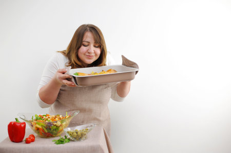 adult curvy woman holding baking sheet with food cooked dinner peppers and olives homemade food restaurant serving on white background space for text cooking show block delicious healthy food dinnerの写真素材