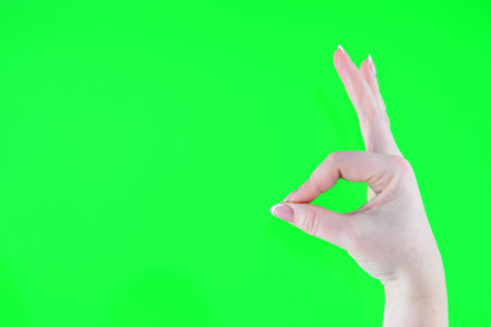 on a green background woman with her hand shows a bunny rabbit with her thumb and forefinger...