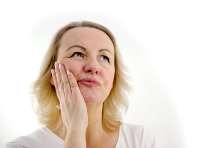 blonde on a white background face close-up hispanic girl wearing casual clothes touching mouth with hand with painful expression because of toothache or dental illness on teeth. dentistの写真素材