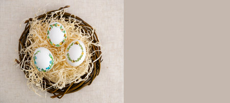 banner a lot of space for text coffee background Easter eggs decorated with painted embroidery ribbons on eggshell in nest three white eggs then on shavings advertising invitation postcard bigboardの写真素材