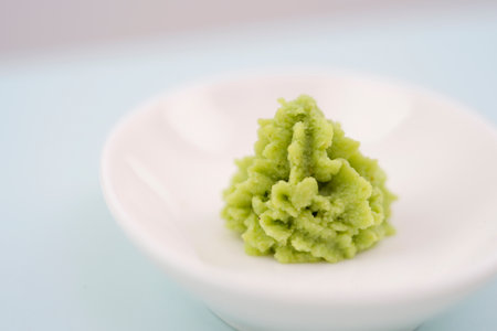 Green wasabi sauce or paste in bowl, with chopsticks or spoon over plain colourful background. selective focusの写真素材