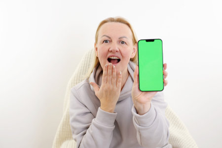 a woman opened her mouth and touched her chin with hand she holds a green screen chromakey phone in...